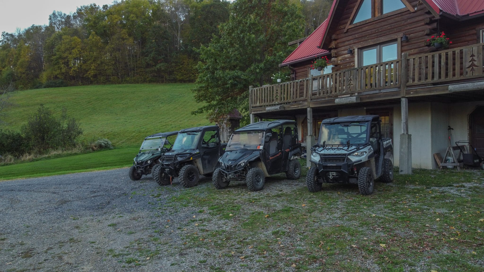 DJI_0516 Clara Creek Company, Four ATVs parked near a log cabin on a grassy hillside.
